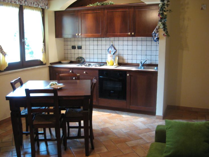 Cucina spaziosa in legno con un tavolo centrale e ampie finestre che lasciano entrare luce naturale.