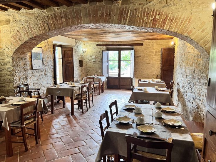 Una semplice sala da pranzo in agriturismo, con tavoli disposti in modo ordinato.