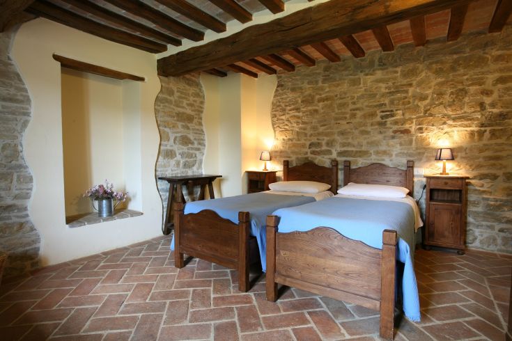 Camera accogliente in agriturismo, arredata con letti in legno e decorazioni semplici.