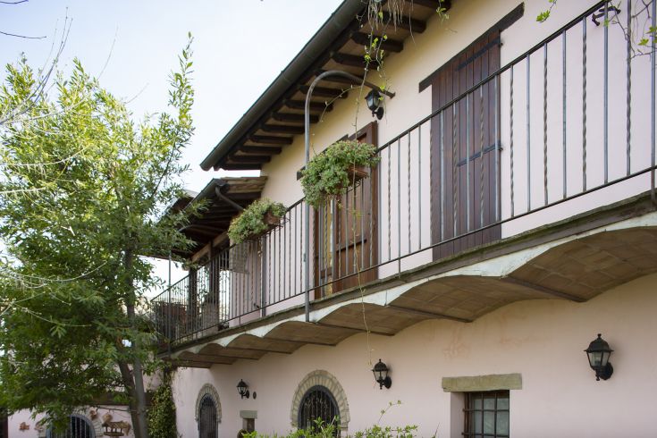 Un casale ristrutturato con balconi e vegetazione, situato nella tranquilla campagna umbra.