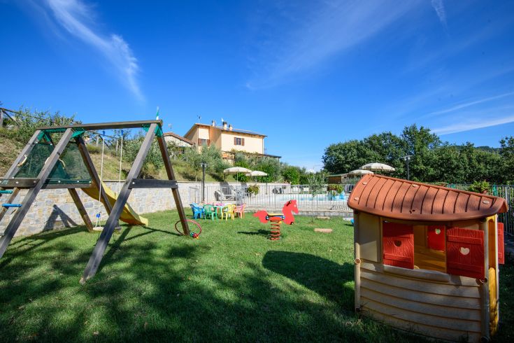 Außenbereich mit Spielplatz in einem Landhaus mit Swimmingpool, umgeben von einer natürlichen Umgebung.
