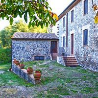 A farmhouse made of stone, surrounded by a large garden and featuring a swimming pool.