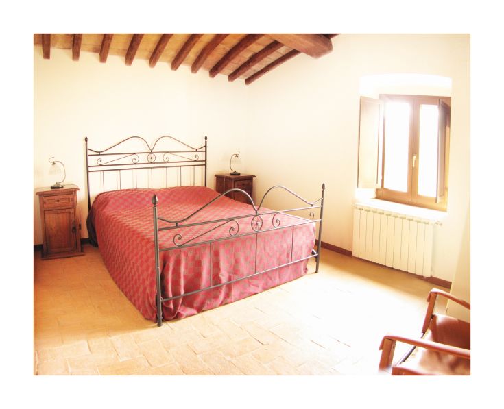 Double room in a farmhouse featuring a wrought iron bed and wooden furniture. Bright ambiance.