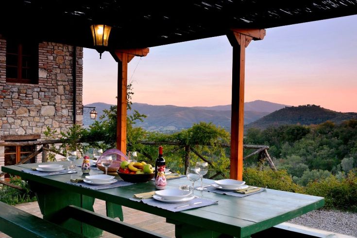 An experience in a farmhouse surrounded by lush hills, with tables set for outdoor lunches and dinners.