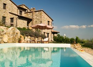 A stone building with a pool, surrounded by the lush greenery of the Umbrian hills.
