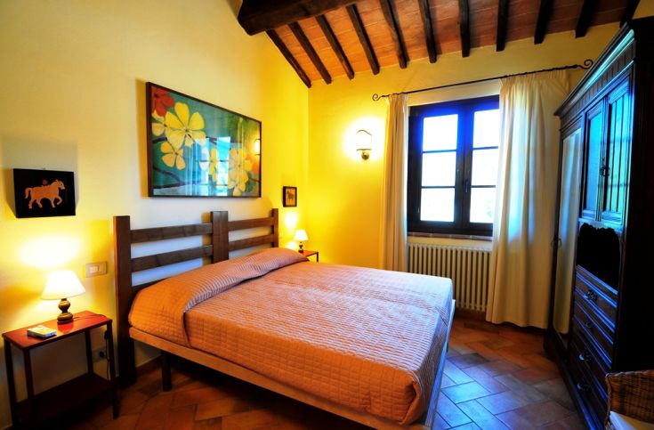 Bright and cozy room with a double bed, floral decorations, and a view of a garden.