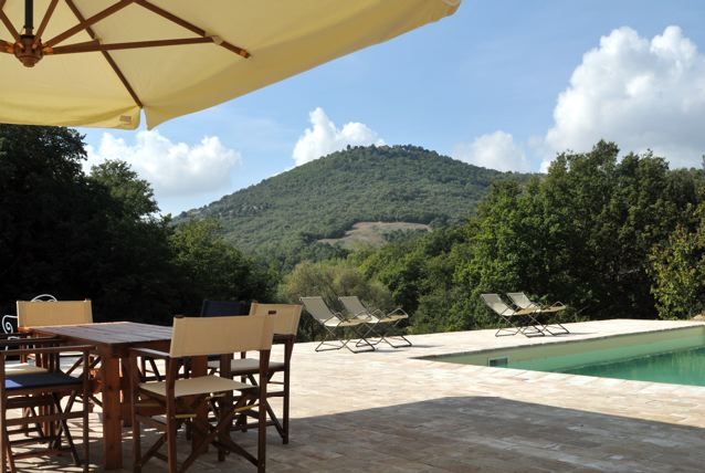 A serene scene from a farmhouse with a pool, surrounded by the green hills nearby.