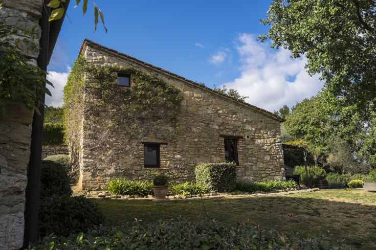 Stone building surrounded by greenery under a clear sky in Umbria.