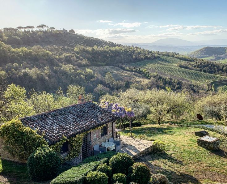 A simple house located in the Umbrian countryside, surrounded by gentle hills and rows of vines.