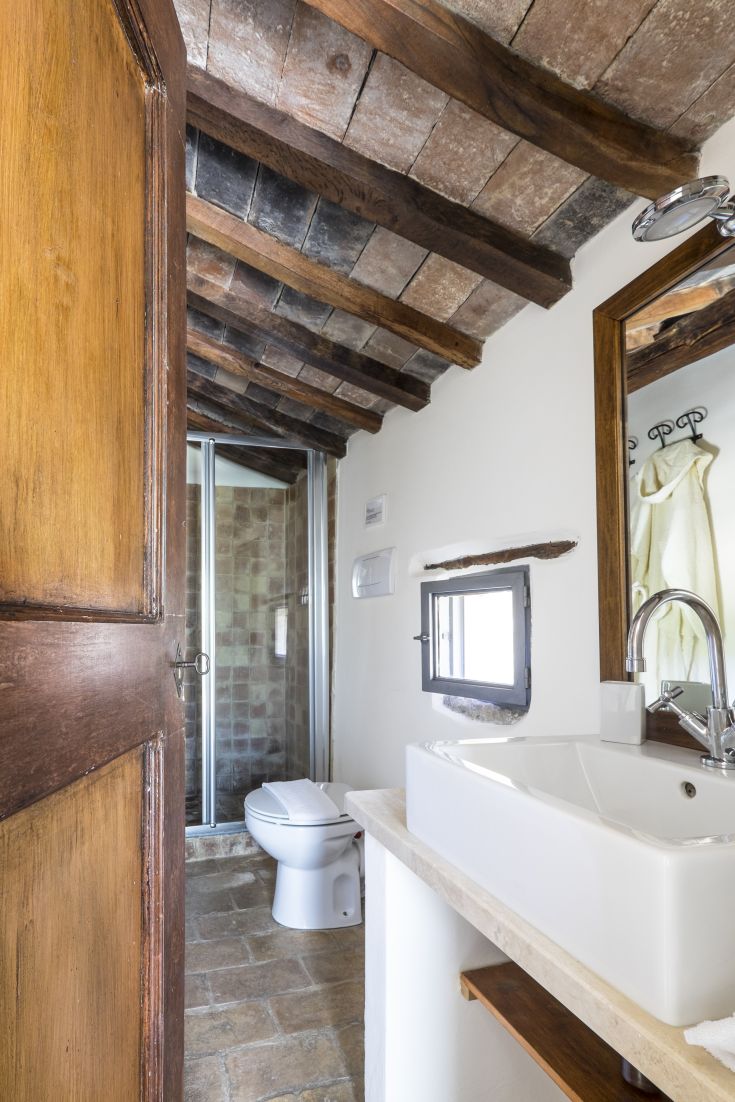 Rustic bathroom with wooden ceiling and light-colored walls.