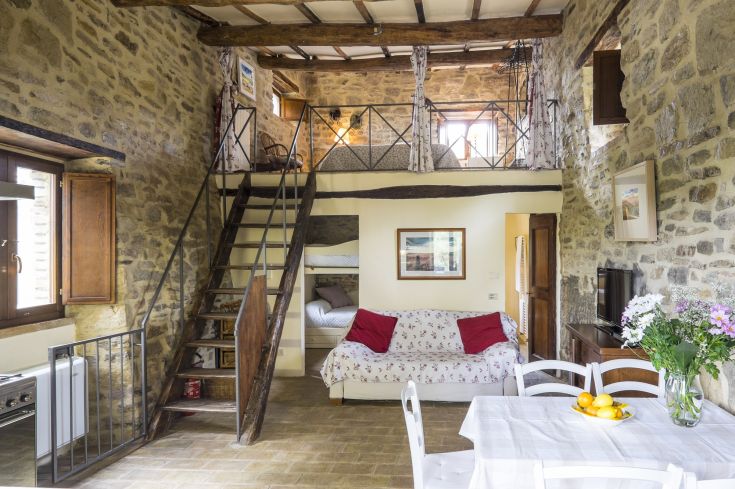 Simple living room with exposed beams and a staircase leading to a loft.