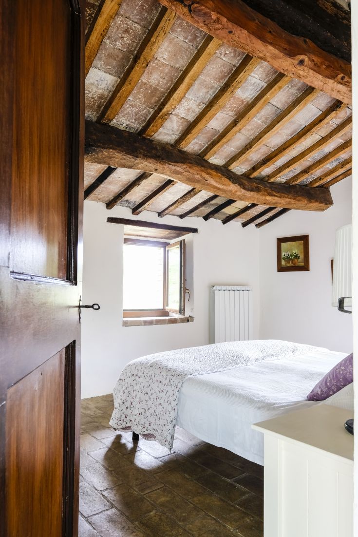 Simple room with exposed beams and a window overlooking a natural landscape.