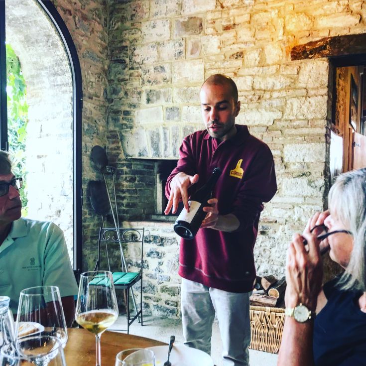 A sommelier explains wine at a classic table, creating a cozy and informal atmosphere.