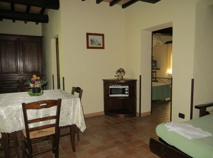 A simple farm stay featuring a table, chairs, and a cooking area.