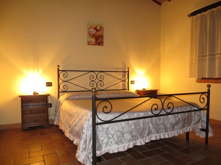 Simple bedroom with a double bed and soft lighting, creating a calm and cozy atmosphere.