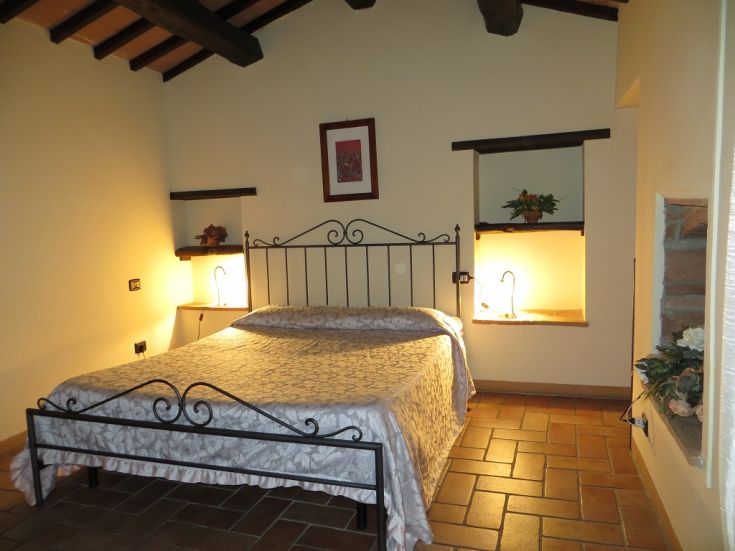 A simple agriturismo room featuring a double bed, rustic elements, and functional furniture.