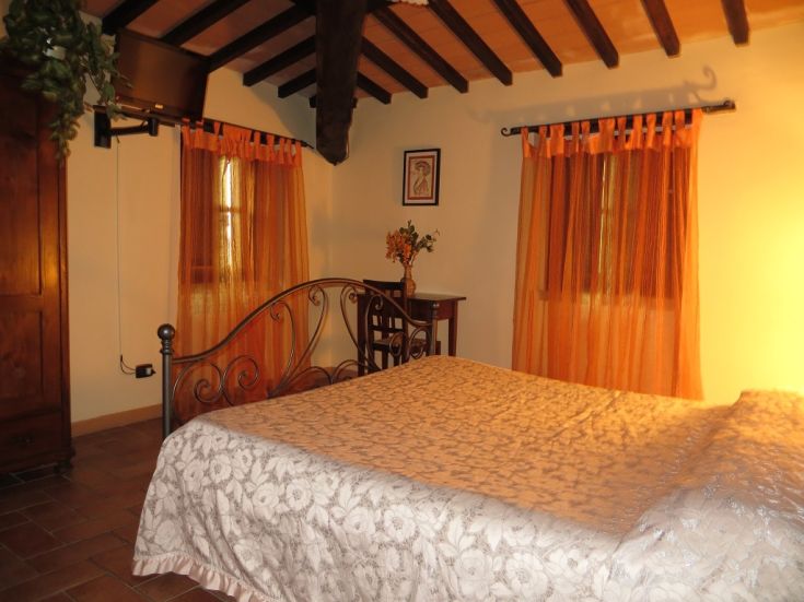 A simple space with a double bed and orange curtains, perfect for a serene stay.