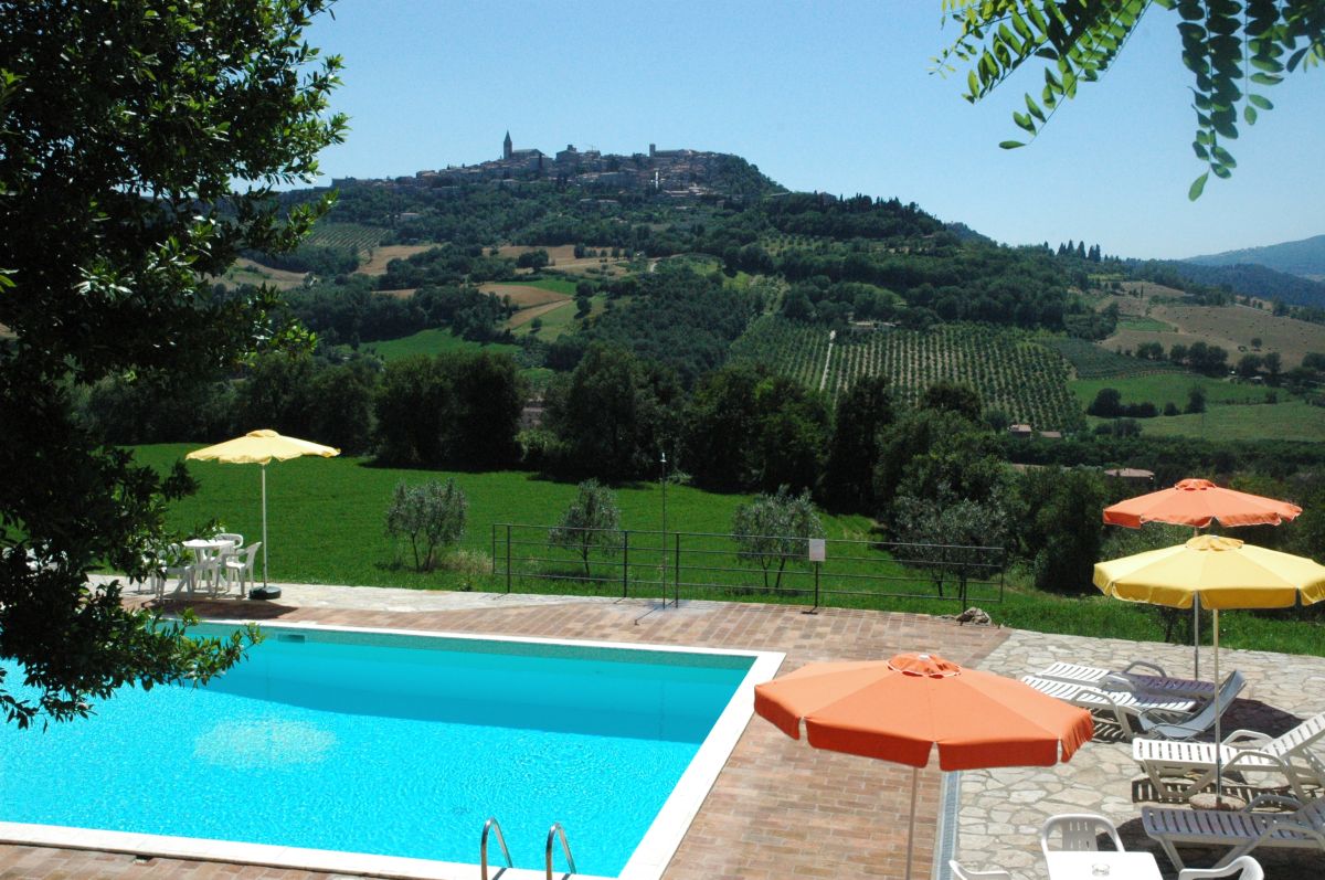 Piscina spaziosa con panorama sulle colline umbre e il profilo della città di Todi in lontananza.