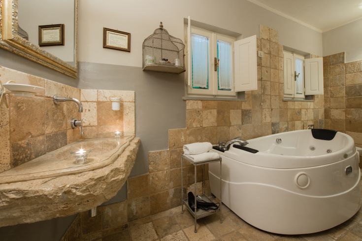 Un bagno raffinato dotato di vasca idromassaggio e dettagli in pietra, caratterizzato da un'atmosfera tranquilla.