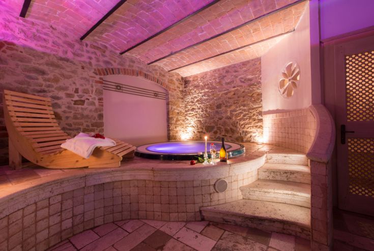 Un'area di relax con vasca idromassaggio e sauna, illuminata con luci calde per un'atmosfera accogliente.