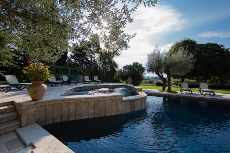 Una piscina all'aperto circondata da un'area verde, con una zona idromassaggio. Ideale per momenti di relax.