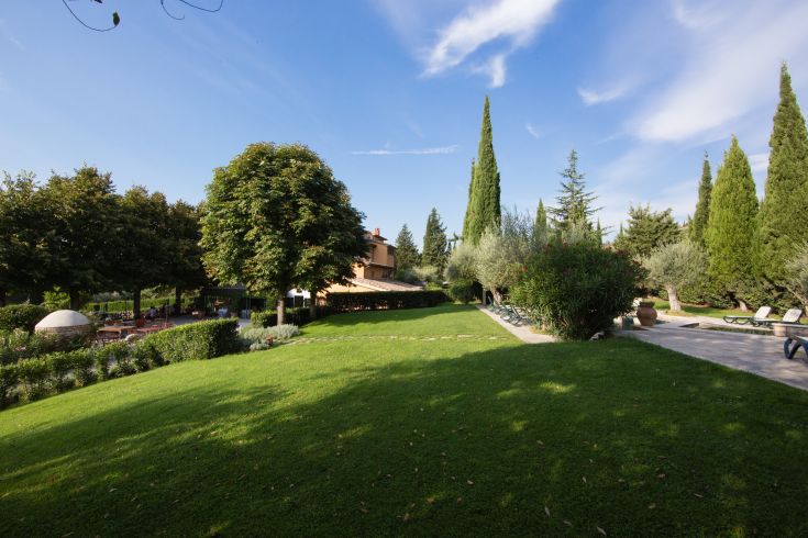 Un giardino sereno con alberi e una costruzione del XIX secolo, adatto per momenti di calma.