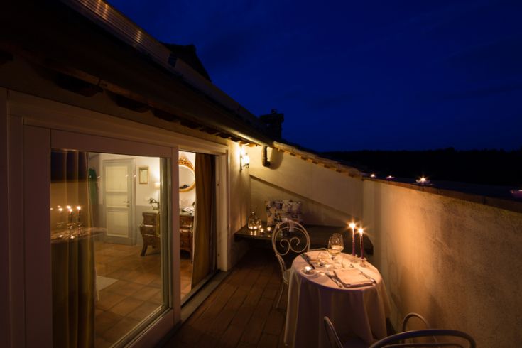 Una cena intima su un balcone, illuminato da candele, con panorama serale suggestivo.