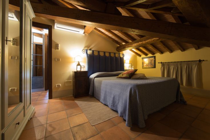 Interno di una camera confortevole con soffitto a travi in legno, arredamento semplice e funzionale.