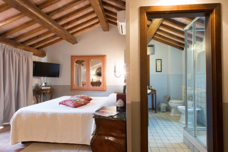 Camera tranquilla con soffitto in legno e bagno annesso, ideale per un soggiorno confortevole.