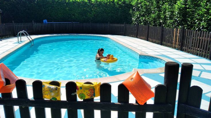 Eine Frau und ein Kind haben Spaß in einem Pool auf einem Schlauchboot. Die Atmosphäre ist friedlich und typisch für einen Sommertag.