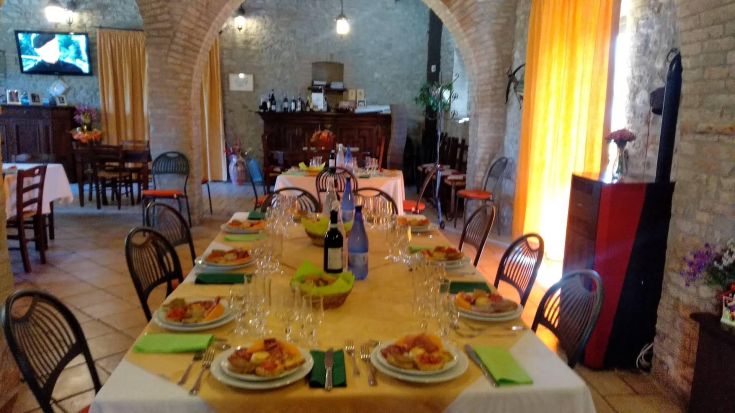 Ein gedeckter Tisch mit Speisen und Geschirr in einer rustikalen Agriturismus-Umgebung, bereit, Gäste zu empfangen.