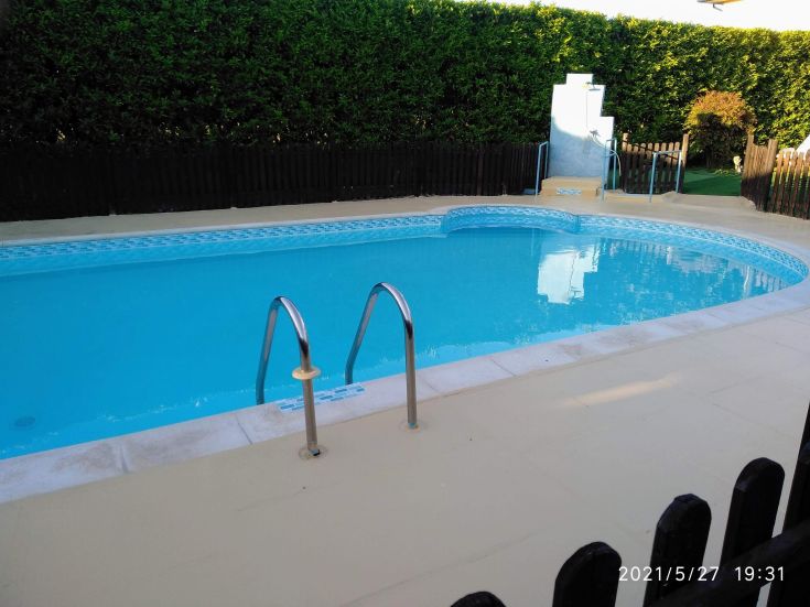 Ein ruhiger Pool, umgeben von einem Holzzaun und üppigem Grün.