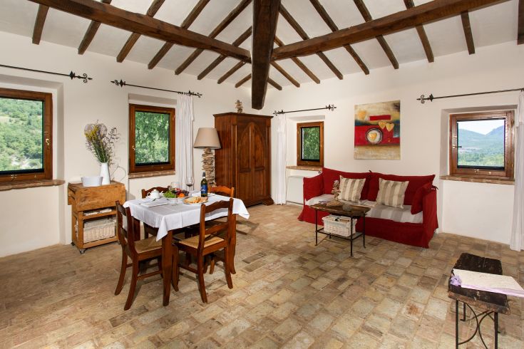 Interior of an Umbrian palace with a decorated table and a view of a natural environment.