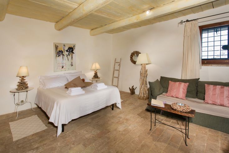 A relaxing bedroom with a bed and sofa, decorated tastefully for a tranquil atmosphere.