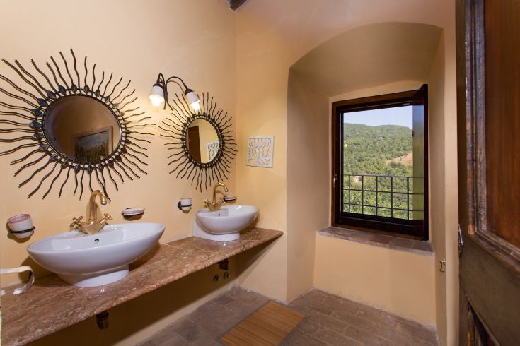 A stylish bathroom featuring two sinks, mirrors, and natural light creating a pleasant atmosphere.
