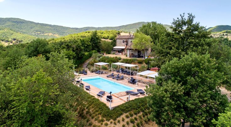 A medieval structure surrounded by lush Umbria greenery, featuring a relaxing pool.