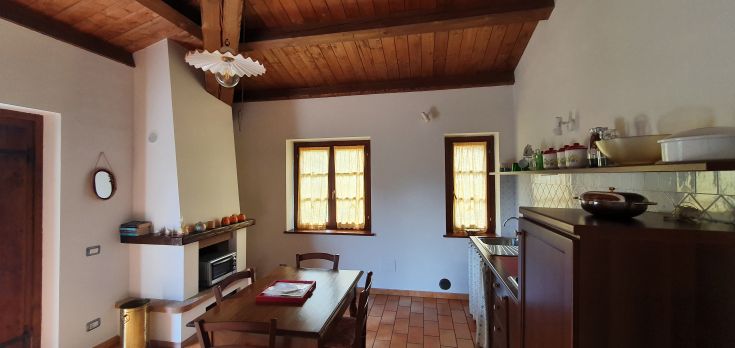 Cuisine simple avec un plafond en bois naturel, une table centrale et des fenêtres qui illuminent l'espace.