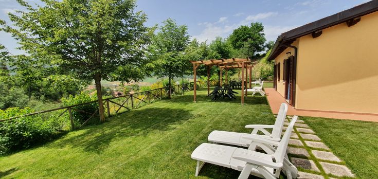 Une zone verte avec des chaises et des zones ombragées, entourée par une végétation luxuriante.