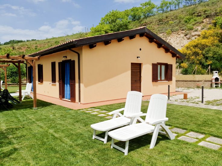 Une maison moderne avec un jardin bien entretenu, comprenant des chaises longues pour se détendre en plein air.