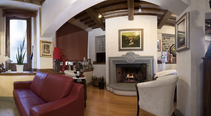 Interno di un palazzo che presenta un camino e arredi semplici, contribuendo a un'atmosfera conviviale.