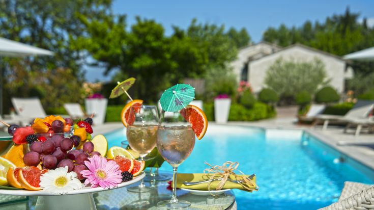 Un angolo tranquillo con bevande e frutta fresca vicino a una piscina, ideale per momenti di relax.