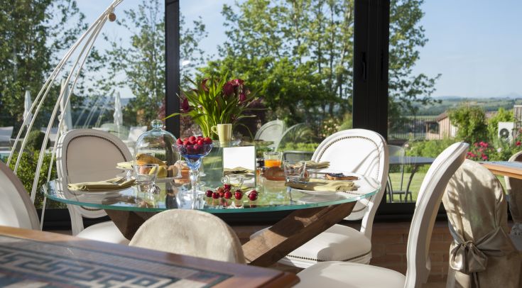 Un tavolo ben apparecchiato con frutta fresca e fiori, situato in un giardino curato.