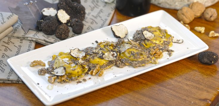 Ravioli ripieni di tartufo e noci, presentati su un semplice piatto bianco.