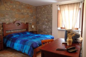 Einfaches Zimmer mit Steinwänden und einem blauen Bett, ideal für einen ruhigen Aufenthalt.