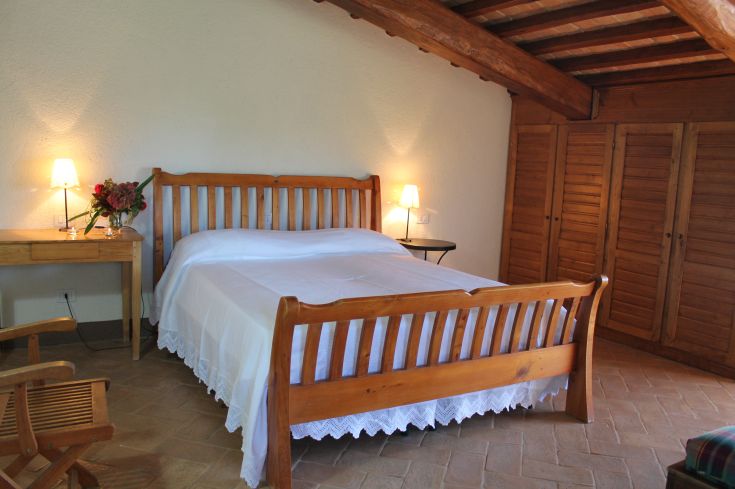 Chambre simple avec un lit double et des meubles en bois, idéale pour un séjour paisible.
