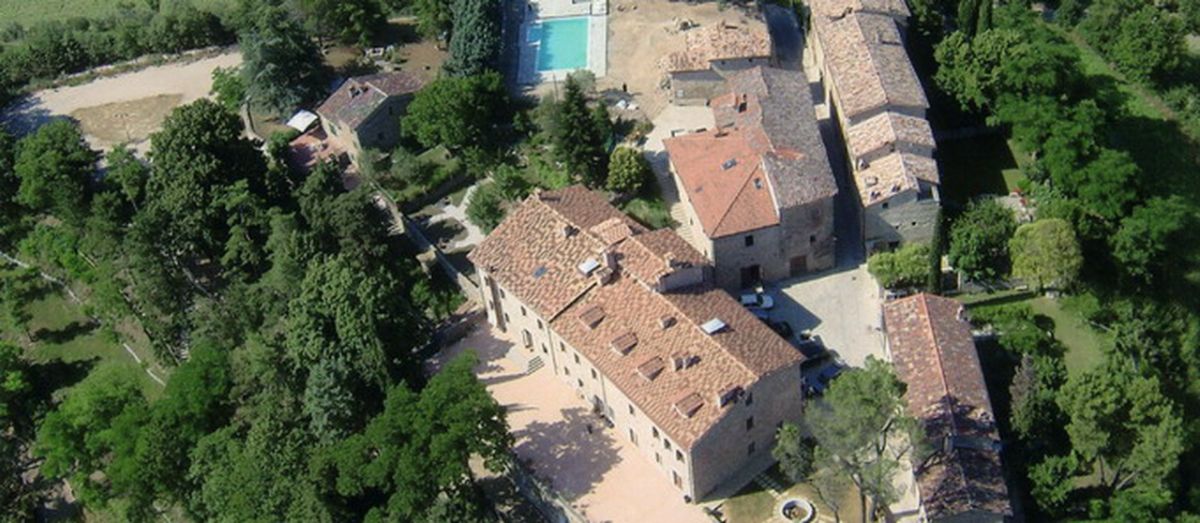 Un paisible village médiéval entouré de la nature, avec une piscine et des bâtiments historiques.