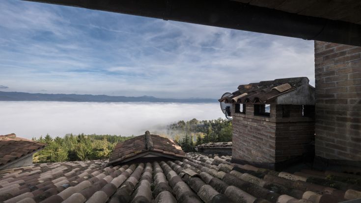 Eine Szene eines Dorfes, das zwischen den Wolken liegt und von üppigem Grün umgeben ist.