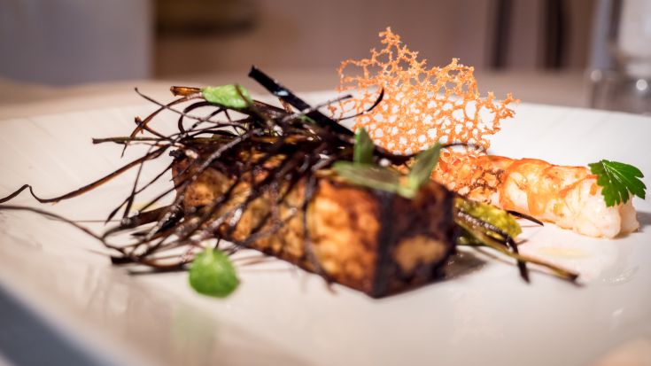 Ein Gericht mit knusprigem Tofu und Garnelen, garniert mit frischen grünen Beilagen.