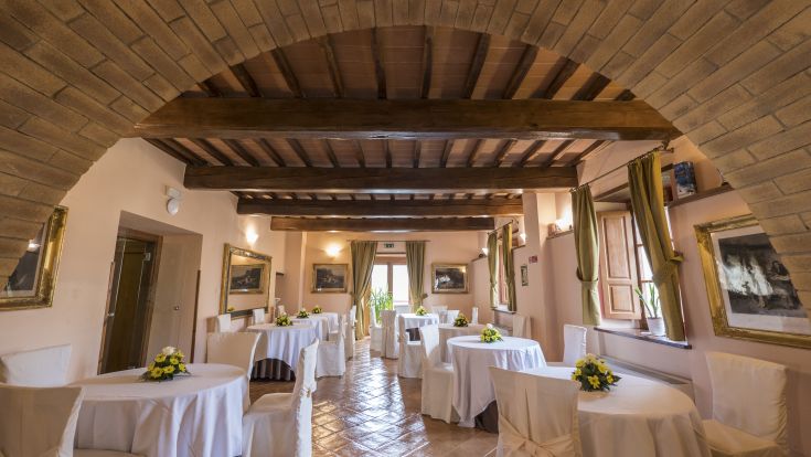 Ein Restaurantbereich mit ordentlich angeordneten Tischen und sichtbaren Holzbalken, ideal für besondere Anlässe.