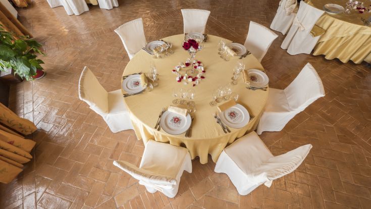 Ein eleganter runder Tisch schön gedeckt, umgeben von weißen Stühlen in einer einfachen und einladenden Umgebung.